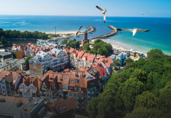 Uitzicht op Kołobrzeg met rode daken, haven en strand, vanuit een vakantiewoning aan zee.