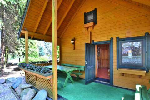 Casa vacanze in legno con veranda coperta, area pranzo esterna e verde a Kołobrzeg, Danimarca.