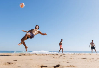 Drie mannen spelen voetbal op het strand bij vakantiewoning Kołobrzeg voor 3 personen in Denemarken.