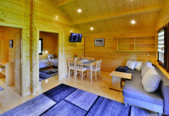 Vista interior de un alojamiento glamping revestido de madera, con muebles modernos y ambiente acogedor.