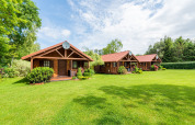 Jolies cabanes en bois aux toits rouges sur pelouse verte, idéales pour une expérience glamping en pleine nature.
