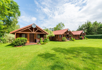 Acogedoras cabañas de madera con techos rojos en césped verde, ideales para una experiencia de glamping.