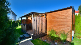 Knusse houten cottage voor twee in Ustronie Morskie, met terras, tuin en stralende blauwe lucht.
