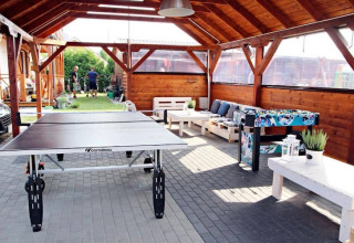 Overdekt terras met tafeltennistafel, tafelvoetbal en zitgedeelte bij een nieuw huisje in Ustronie Morskie.
