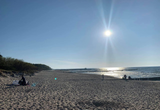 Zonnig strand bij 'Year-round new cottage for 2 people Ustronie Morskie' met enkele mensen aan zee.