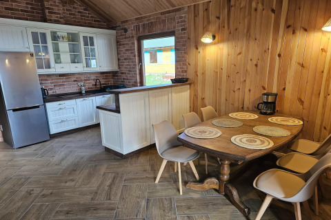 Cucina rustica in lodge con pareti in legno, tavolo da sei posti, frigorifero moderno e macchina da caffè.