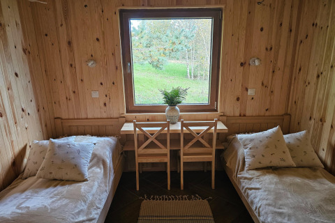 Gezellige lodgekamer met twee eenpersoonsbedden, houten wanden en een raam met uitzicht op groen.