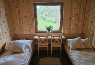 Et hyggeligt værelse på en lodge med to enkeltsenge, træpaneler og et vindue med udsigt til naturen.