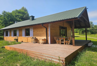 Houten lodge met ruim terras en veranda, omgeven door groen, ideaal om buiten te ontspannen bij mooi weer.