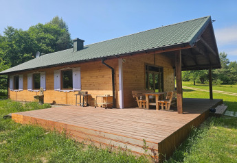 Cabaña de madera con amplia terraza exterior rodeada de naturaleza, ideal para descansar al aire libre.