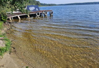Foto van een steiger en helder water bij een lodge, met uitzicht op een rustige oever van het meer.