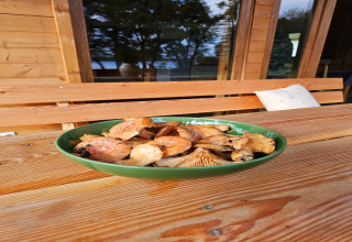 En grøn skål med svampe på et træbord ved LAWENDA sommerhus, udendørs, i Grąbczyn, Danmark.
