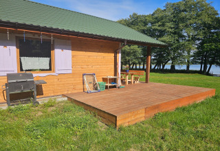 Vakantiehuisje van hout met groen dak en terras, barbecue bij het meer in Grąbczyn, Denemarken.