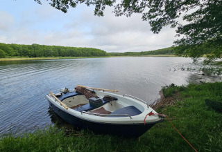 Boot aangemeerd aan het meer met bos op de achtergrond bij LAWENDA vakantiehuis, Grąbczyn, Denemarken.