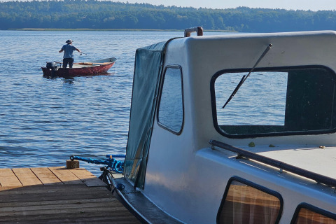 Two boats on a lake at LAWENDA holiday cottage in Grąbczyn, Denmark, with a person fishing in the distance.