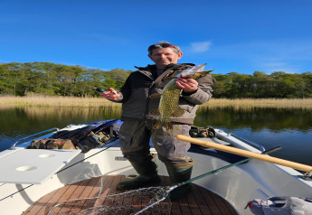 Hombre pescando en un bote en LAWENDA casa de vacaciones en Grąbczyn, Dinamarca, muestra un pez.