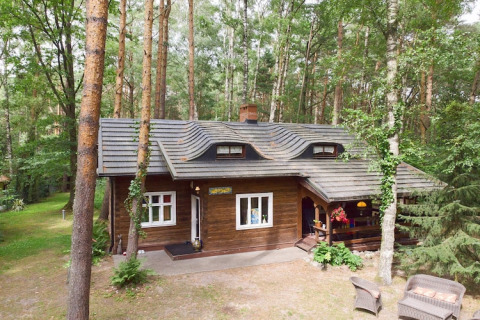 Vue extérieure du Holiday home Debki, un lodge en bois rustique entouré de hauts arbres de forêt.