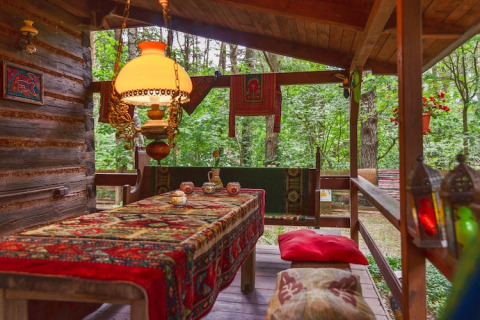 Véranda chaleureuse à Holiday home «Debki» en Suède, tapis oriental, lampe vintage, vue sur la forêt.