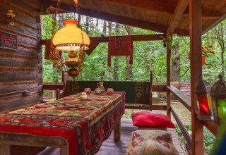 Véranda chaleureuse à Holiday home «Debki» en Suède, tapis oriental, lampe vintage, vue sur la forêt.