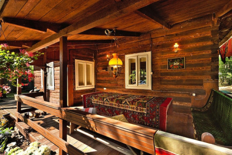 Cabane en bois avec véranda chaleureuse, bancs et tapis colorés au Holiday home «Debki» en Suède.