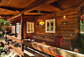 Cabane en bois avec véranda chaleureuse, bancs et tapis colorés au Holiday home «Debki» en Suède.