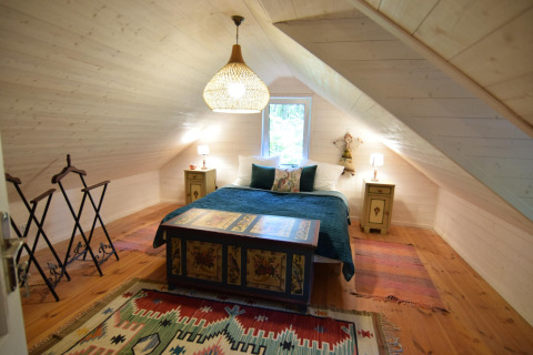 Et hyggeligt soveværelse med skrå loft, dobbeltseng og farverige tæpper i Holiday home «Debki» i Sverige.