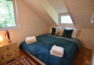 Chambre chaleureuse avec lit double, couvre-lit vert et murs en bois au Holiday home «Debki» en Suède.