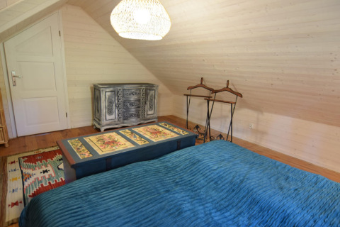 Chambre à Holiday home «Debki» en Suède avec couvre-lit bleu, commode et plafond en bois incliné.