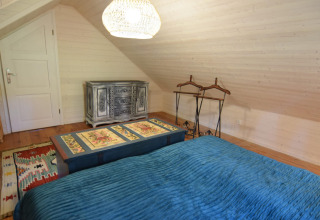 Chambre à Holiday home «Debki» en Suède avec couvre-lit bleu, commode et plafond en bois incliné.