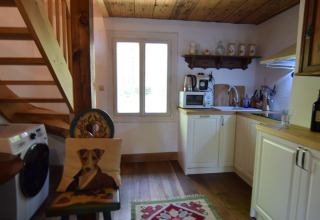 Cuisine chaleureuse dans un gîte suédois, plafond en bois, machine à laver et chaise avec coussin chien.