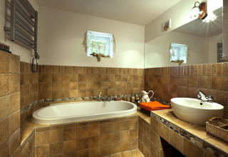 Salle de bain chaleureuse à Holiday home «Debki» en Suède avec carrelage marron, baignoire et lavabo.