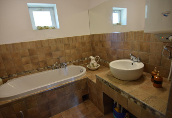 Baño con bañera, lavabo y espejo en la casa de vacaciones «Debki» en Suecia, de estilo rústico.