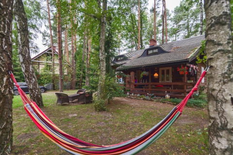 Hamac coloré installé entre des arbres devant le gîte «Debki» en Suède et son chalet chaleureux.