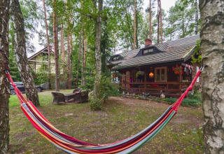 Udendørsområde ved Holiday home «Debki» i Sverige med farverig hængekøje og hyggelig bjælkehytte.