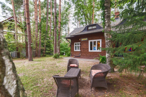 Coin salon extérieur avec fauteuils en osier devant un chalet en bois à Holiday home «Debki» en Suède.