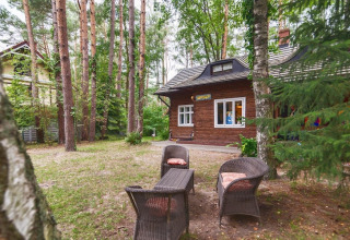Coin salon extérieur avec fauteuils en osier devant un chalet en bois à Holiday home «Debki» en Suède.