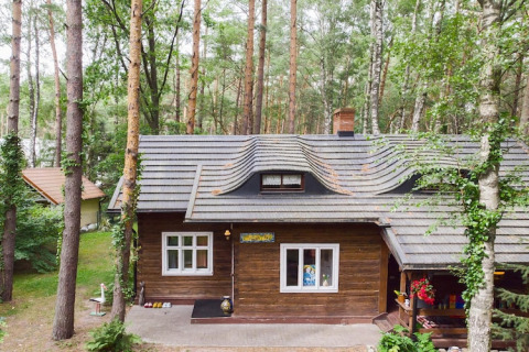 Et hyggeligt træhus i skoven ved Holiday home «Debki» i Sverige, omgivet af høje træer og natur.