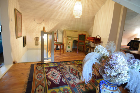Grenier chaleureux au Holiday home «Debki» en Suède avec tapis coloré et bureau ancien vintage peint.