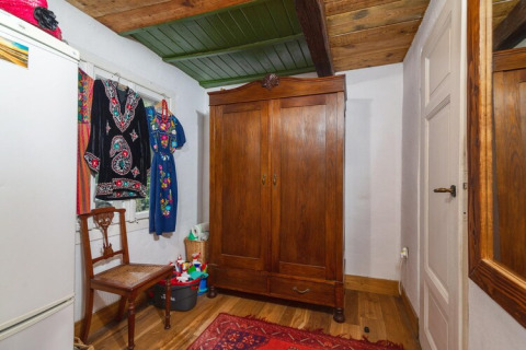 Chambre suédoise traditionnelle au Holiday home «Debki» avec armoire en bois, chaise, miroir et robes colorées.