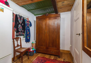 Chambre suédoise traditionnelle au Holiday home «Debki» avec armoire en bois, chaise, miroir et robes colorées.
