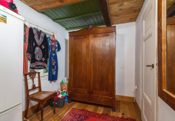 Traditionele Zweedse kamer in Holiday home «Debki» met houten kast, stoel, spiegel en hangende jurken.