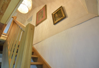 Escalier en bois avec rampe dans la maison de vacances Debki en Suède, vue vers deux tableaux et une lampe.
