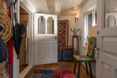 Entrée chaleureuse d’une maison de vacances suédoise avec meubles peints et tapis coloré au sol.