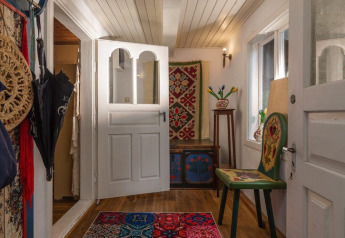 Ingresso accogliente di casa vacanze svedese con mobili dipinti e tappeto colorato tradizionale.