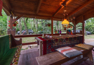 Espace détente extérieur au Holiday Home «Debki» en Suède, avec bancs, textiles colorés et lampes suspendues.