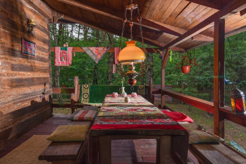 Véranda en bois du Holiday home «Debki» en Suède, ornée de coussins colorés et lampe suspendue.