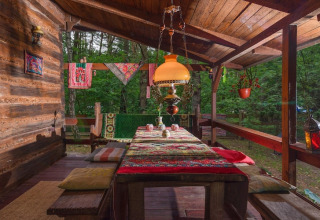 Træveranda ved Holiday home «Debki» i Sverige med farverige tæpper, puder og lyst hængende lampe.