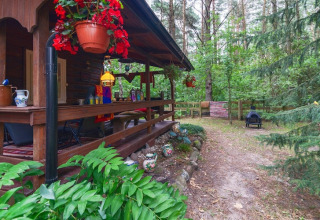 Cabane en bois avec terrasse couverte, fleurs suspendues et vue sur la forêt à Holiday home «Debki», Suède.