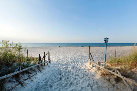 Sandsti fører til rolig strand og blåt hav ved Holiday home «Debki», omgivet af grøn vegetation og træhegn.