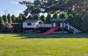Parco giochi presso casa vacanze a Świnoujście con scivolo, altalene e casetta, circondato da alberi.